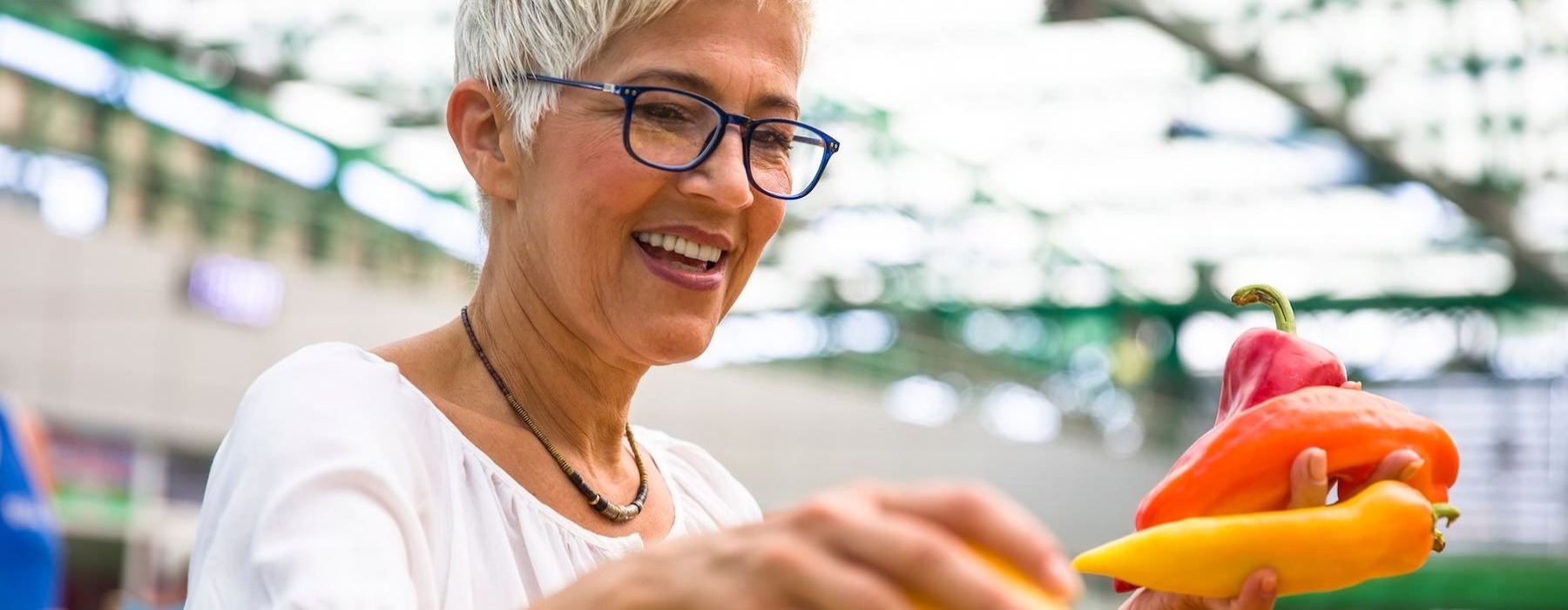 a woman smiling and holding a bunch of vegetables